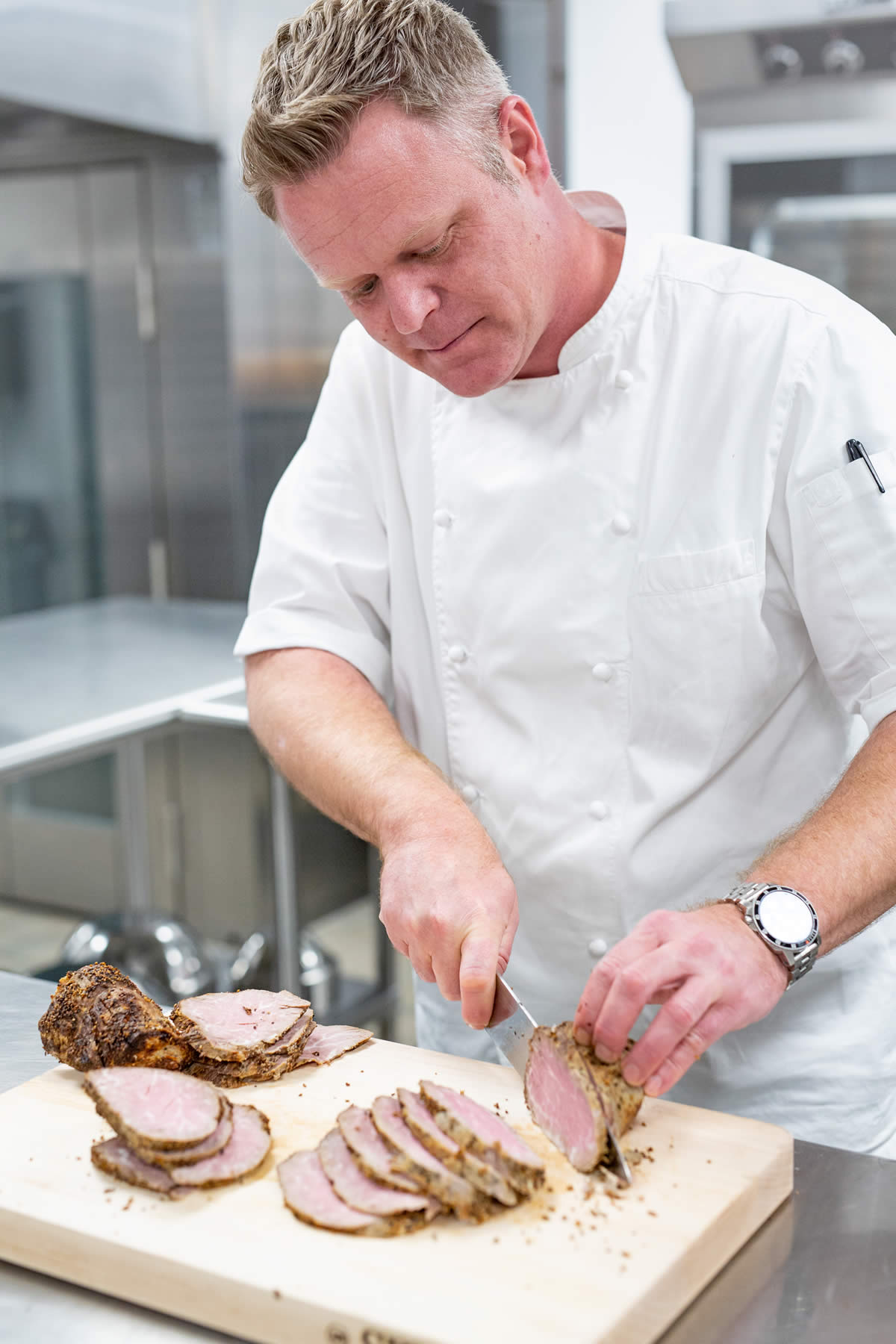 Chef Balster slicing a roast on a wooden cutting board.